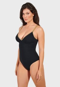 Svart baddräkt i en del med djup V-ringning, guldaccentband, slät textur och en figurnära silhuett som framhäver formen.
