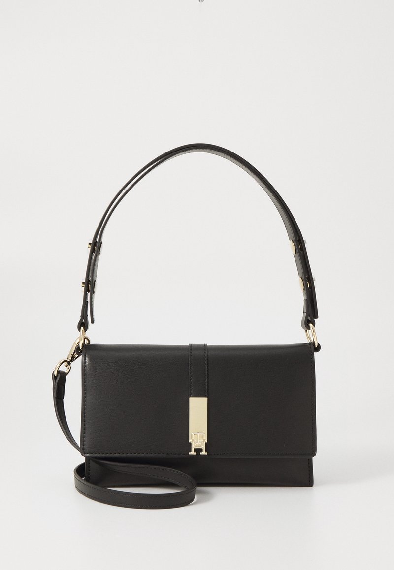 Sac à main rectangulaire en cuir noir avec fermoir doré, bandoulière courte réglable et bandoulière longue supplémentaire portée en travers du corps, sur fond uni.