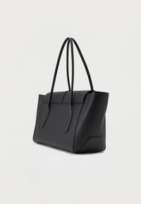 Μαύρη δερμάτινη τσάντα χειρός με δύο μακριές λαβές, σχεδιασμός με δομή και διακριτικό λογότυπο μάρκας στο εμπρός μέρος, σε ελαφρώς κεκλιμένη θέση σε λευκό φόντο.