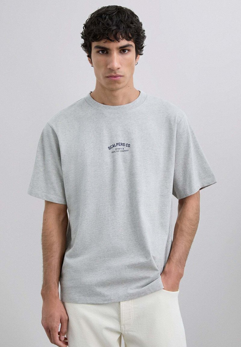 Camiseta de algodón gris con mangas cortas, escote redondo y bordado en azul marino "SCALPERS CO" en el pecho. Diseño simple y de corte relajado.