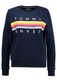 Mörkblå crewneck sweatshirt med horisontella gula, rosa, röda och ljusblå ränder samt texten "TOMMY JEANS" ovanför och nedanför ränderna.