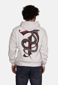 Felpa bianca con una grande grafica di un serpente nero e rosso e il design della lettera 'P' sul retro. Il materiale sembra morbido, con polsini e orlo a coste.