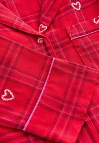 Czerwone piżamy w kratkę wykonane z miękkiego materiału, z guzikami, różowymi akcentami oraz haftowanymi serduszkami na piersi i rękawach.