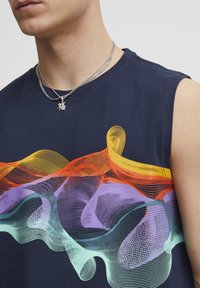 Maglietta senza maniche blu navy con una grafica di onde in gradiente nei colori arancione, giallo, viola e turchese. Collane a catena argentate incluse.