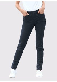 Donkerblauwe skinny jeans van denim, met een hoge taille, twee voorzakken en een enkele knoopsluiting. Gekleed met een wit shirt en sneakers.