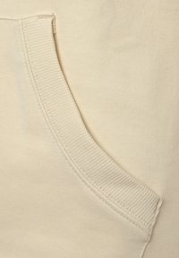 Beige Sweatshirtstoff mit Kängurutasche, gerippter Textur an den Rändern und glatter Oberfläche insgesamt.