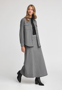 Grijze denim overhemd, gelaagd over een zwart top, in combinatie met een bijpassende grijze denimrok. Draag het met zwarte hakken enkellaarsjes. Glad textuur.