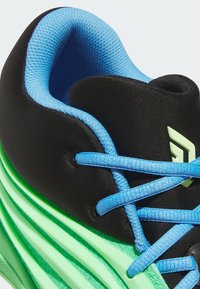 Scarpa sportiva nera con lacci blu, caratterizzata da un upper nero testurizzato, una suola verde ondulata e un logo prominente in verde pallido.