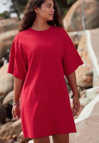 Rød bomulds T-shirt kjole med korte ærmer, afslappet pasform og glat tekstur. Bæres afslappet, velegnet til varmt vejr.