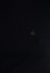 Sort ribbet tanktop med et subtilt broderet logo. Teksturen er glat med et tætsiddende design.