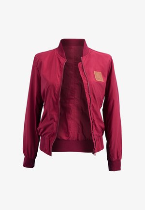 Burgunderfarbene Bomberjacke mit Reißverschluss, gerippten Bündchen und Saum. Ausgestattet mit einem beigen Etikett auf der Brust, glatter Textur und leichtem Material.