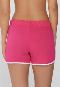 Shorts de sport roses avec une taille élastique et une bordure blanche à l'ourlet. Fabriqués dans un tissu doux, conçus pour le confort et la mobilité.