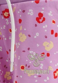 Lila, blumenmusterbezogene Stoff mit roten, gelben und weißen Akzenten. Verfügt über einen weißen Kordelzug und ein besticktes "hummel"-Logo in Silber.