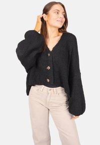 Schwarze Strickjacke mit einem verkürzten Design, tiefem V-Ausschnitt und großen Knopfverschlüssen. Verfügt über voluminöse Ärmel und eine strukturierte Verarbeitung.