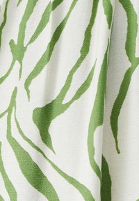 Tessuto bianco con strisce verdi ondulate che creano un motivo strutturato. Il materiale appare morbido e leggero con una finitura liscia.