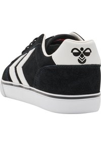 Czarne zamszowe trampki z białymi skórzanymi akcentami, o teksturowanej powierzchni i trzech skośnych białych paskach. Logo umieszczone na pięcie.