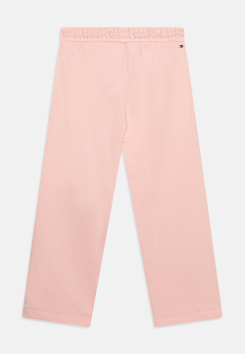 Jasnoróżowe spodnie bawełniane o luźnym kroju, z elastycznym paskiem w talii oraz bez widocznych szwów i kieszeni. Gładka faktura i szerokie nogawki.
