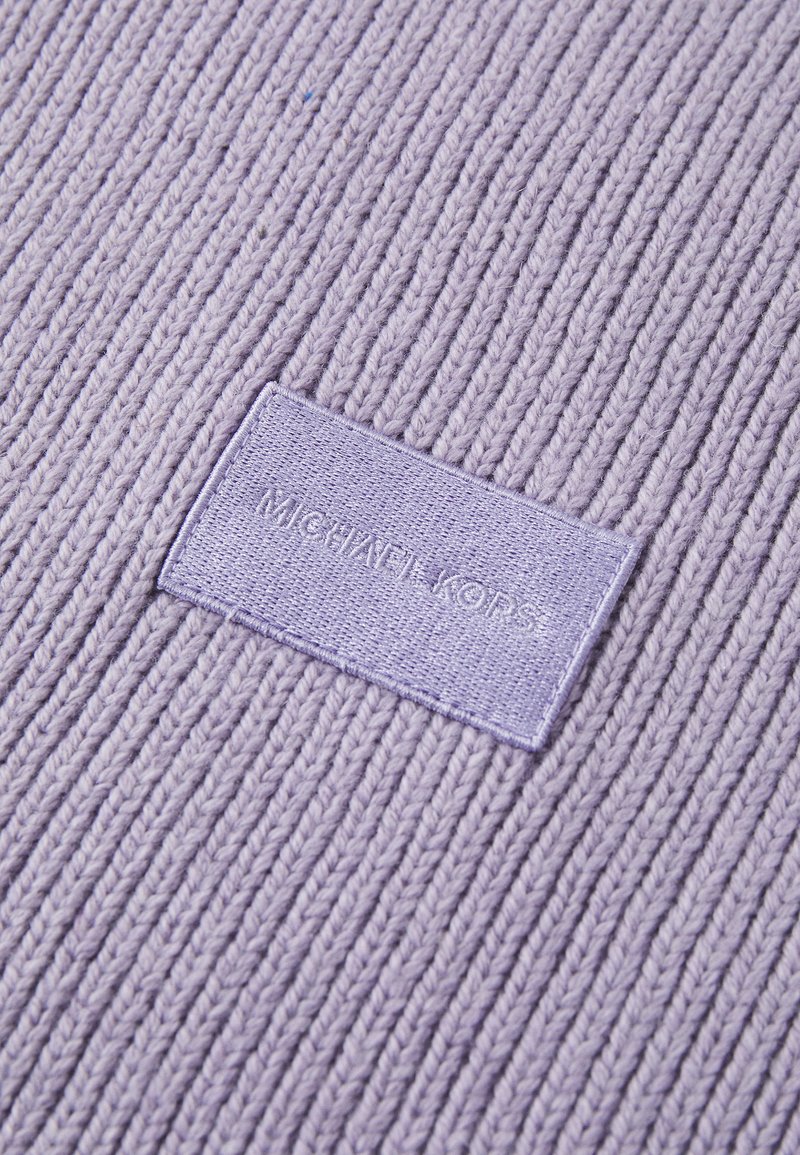 Liliowa dzianina o prążkowanej strukturze, z prostokątną metką, na której znajduje się wytłoczone napisy "Michael Kors".