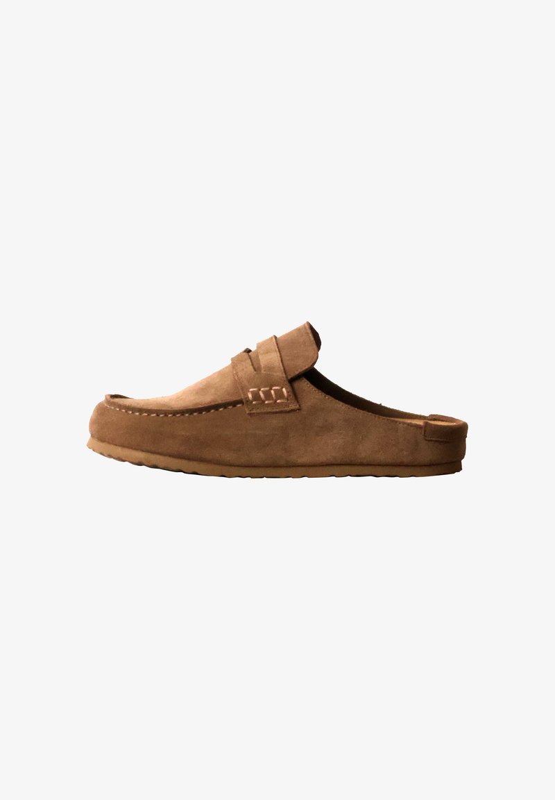 Mocassin marron en daim, sans lacets, avec une semelle en caoutchouc plate et une bride décorative sur le dessus, présenté de profil sur fond blanc.