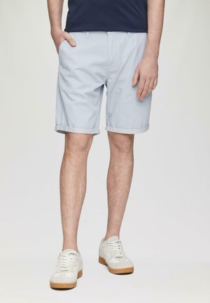 Lichtblauwe katoenen shorts met omgeslagen pijpen, aangesloten zakken en een relaxte pasvorm, gecombineerd met witte sneakers met een tankleurige zool.