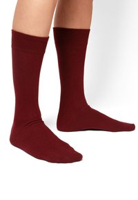 Calzini bordeaux realizzati in un morbido e liscio tessuto. Design al ginocchio con polsini a costine e punta senza cuciture per il massimo comfort.
