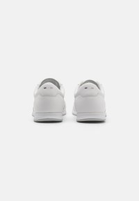 Hvite sneakers med en glatt læroverdel, polstret krage og teksturert såle. Minimalistisk design med subtil merkevare på hælen.