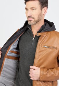 Brun læderjakke med grå hættetrøjeforing, der har en lynlåslomme, glat tekstur og stilfulde indvendige detaljer.