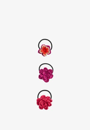 Three crochet flower hair ties in pink, red, and purple shades, each attached to a black elastic band on a white background.