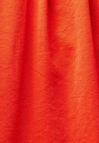 Jasně červená tkanina s hladkým povrchem, která má jemný lesk a diagonální vazbu, elegantně splývá.