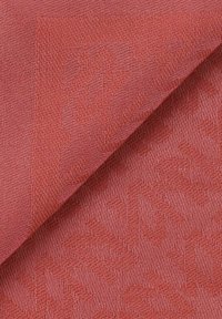 Textielstof in een matte koraalkleur met een subtiel patroon. De textuur is iets ruw en toont geweven details aan de randen.