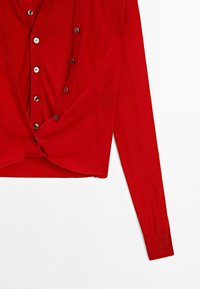 Röd långärmad cardigan med djup V-hals, prydd med knäppning i silverfärgad ton och tillverkad av ett mjukt, lätt tyg. Kort längd med en avslappnad passform.