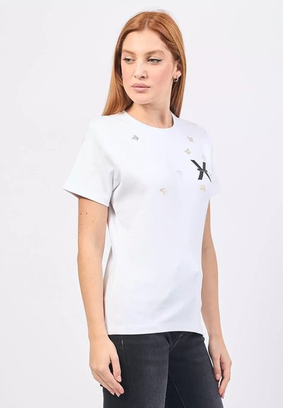 T-shirt bianca in cotone a maniche corte, con logo nero e dettagli a forma di stella metallici in argento e oro. Design classico con scollo a girocollo.