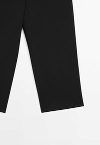 Musta räätälöity housut, valmistettu kevyestä kankaasta, joissa on suora lahkeen leikkaus ja hienot ompelu Yksityiskohdat saumoissa.