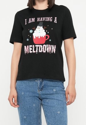 T-shirt noir avec un bonhomme de neige qui fond dans une tasse rouge et le texte "I am having a meltdown,", porté avec un jean bleu à petits motifs floraux blancs.