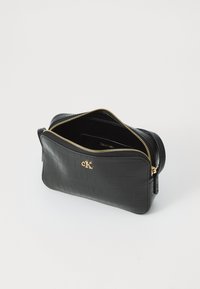 Svart läderväska med krokodilstruktur, guldtonad dragkedja och en liten logotypdetalj. Insidan är fodrad i svart med en ficka.