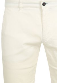 Cremfarbene Baumwollhosen mit glatter Textur, ausgestattet mit einem klassischen Fünf-Taschen-Design und einem einzelnen schwarzen Knopfverschluss.