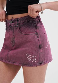 Roze denim minirok met vervaagde textuur, voorzien van een witte geborduurde ontwerpen en een knoopsluiting. Shorts zoomlijn en standaardzakken.