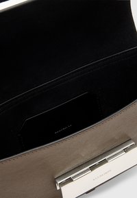 Ruskea nahkalaukku, jossa on hopeinen solki, mustalla samettivuorilla ja sisällä korttipohja. Silkkinen pinta ja tarkka ommel.