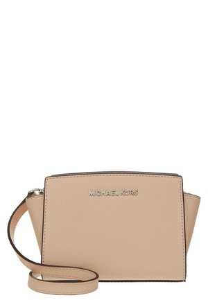 Beżowa torebka na ramię Michael Kors z teksturowanym wykończeniem, srebrnym logo z przodu i regulowanym paskiem zwiniętym z przodu.