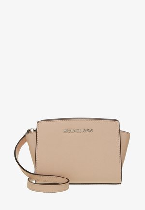 Beżowa torebka na ramię Michael Kors z teksturowanym wykończeniem, srebrnym logo z przodu i regulowanym paskiem zwiniętym z przodu.