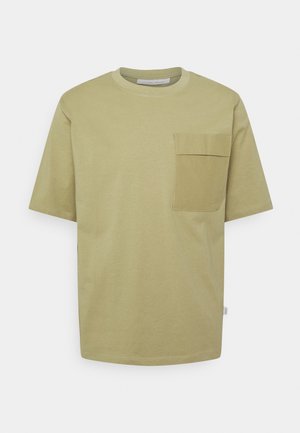 T-shirt vert olive en coton doux, avec un col rond et une poche rectangulaire sur le côté gauche de la poitrine. Manches courtes.
