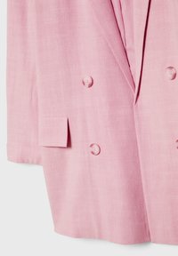 Vaaleanpunainen kaksirivinen bleiseri, jossa on viistetyt läpät, kaksi nappia kummallakin puolella ja suorakulmainen läppätasku alavasemmalla puolella.