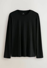 Camiseta negra de manga larga hecha de algodón, con cuello redondo y bajo recto. Presenta una textura suave y un corte relajado. Sin estampados ni detalles.