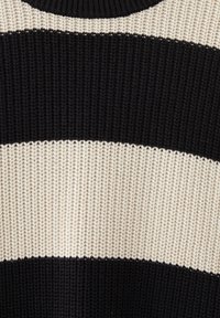 Sweter dziergany w naprzemienne szerokie pasy czarne i kremowe. Posiada prążkowaną teksturę oraz klasyczny krój z okrągłym dekoltem.