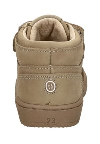 Beige kinderboot van zacht suède materiaal, met een gevoerde kraag en klittenbandsluiting. Voorzien van een circulair logo en een gestructureerde zool met maatmarkering.