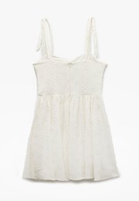 Vestido blanco sin mangas con tirantes ajustables, tela texturizada que presenta patrones florales, un corsé ajustado y una falda fruncida.