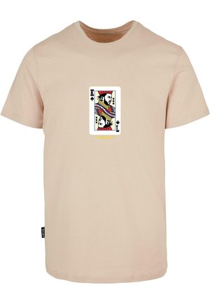 Beige pamut póló, amelyen színes királyi kártya grafikája látható a mellrész közepén.