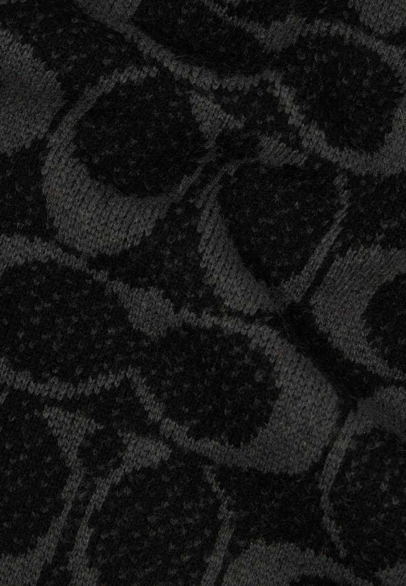 Schwarzer und grauer strukturierter Strickstoff mit einem kreisförmigen Muster, das unterschiedliche Tiefen aufweist und visuelles Interesse am Material erzeugt.