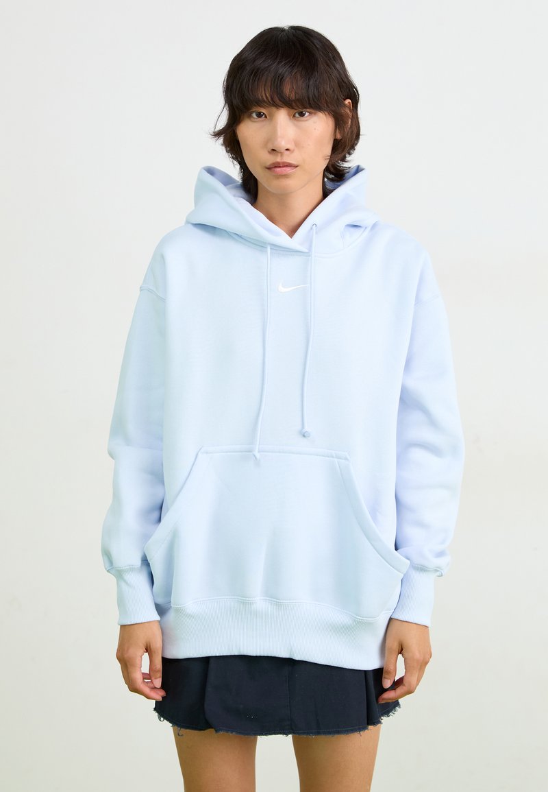 Sweatshirt azul claro com um bolso frontal, cordões ajustáveis e um pequeno logo da Nike em branco. Feito de material suave, possui punhos canelados.
