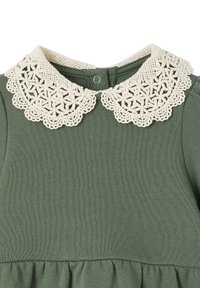 Grünes Kleid mit einem dekorativen, gehäkelten Elfenbeinkragen mit blumigen Mustern und einer Knopfverschluss hinten. Weicher, strukturierter Stoff.